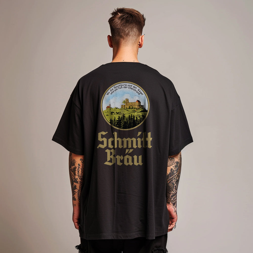 mann in studio trägt ein oversized schwarzes tshirt mit schmitt bräu logo